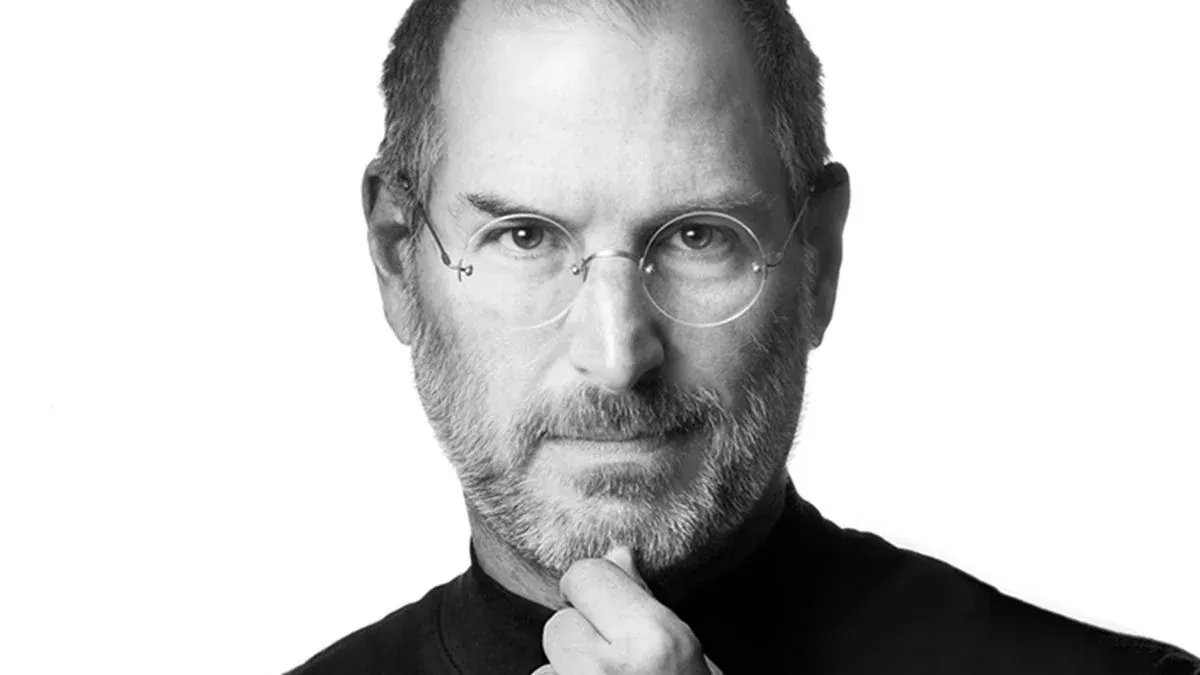 Black and white portrait of Steve Jobs resting his chin on his hand.